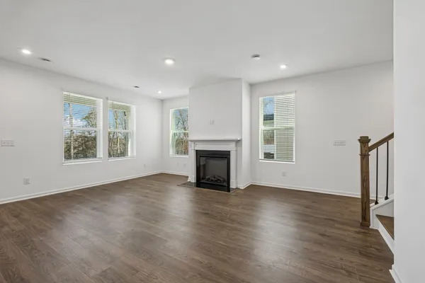 an empty room with wooden floor fireplace and windows