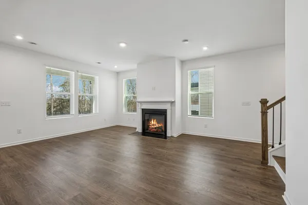 an empty room with wooden floor fireplace and windows