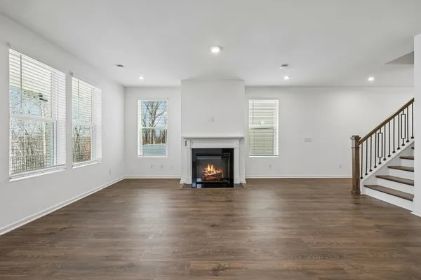 a view of an empty room with wooden floor fireplace and a window
