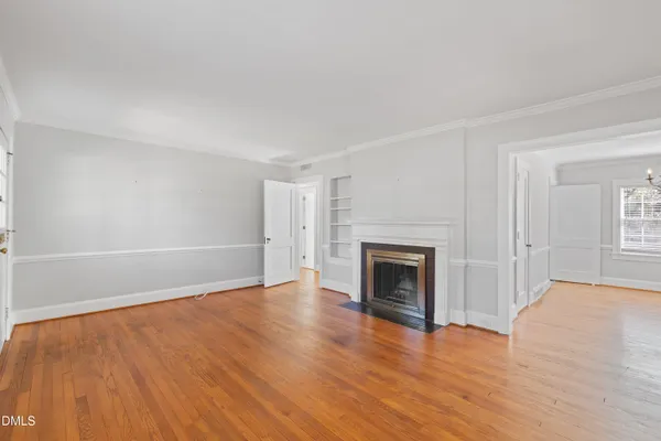 an empty room with wooden floor fireplace and windows
