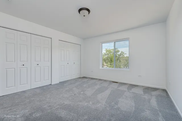 a view of an empty room with closet and a window