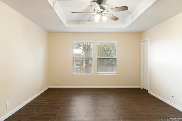 an empty room with wooden floor fan and windows
