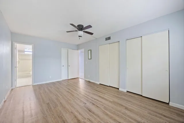 a view of empty room with wooden floor and fan