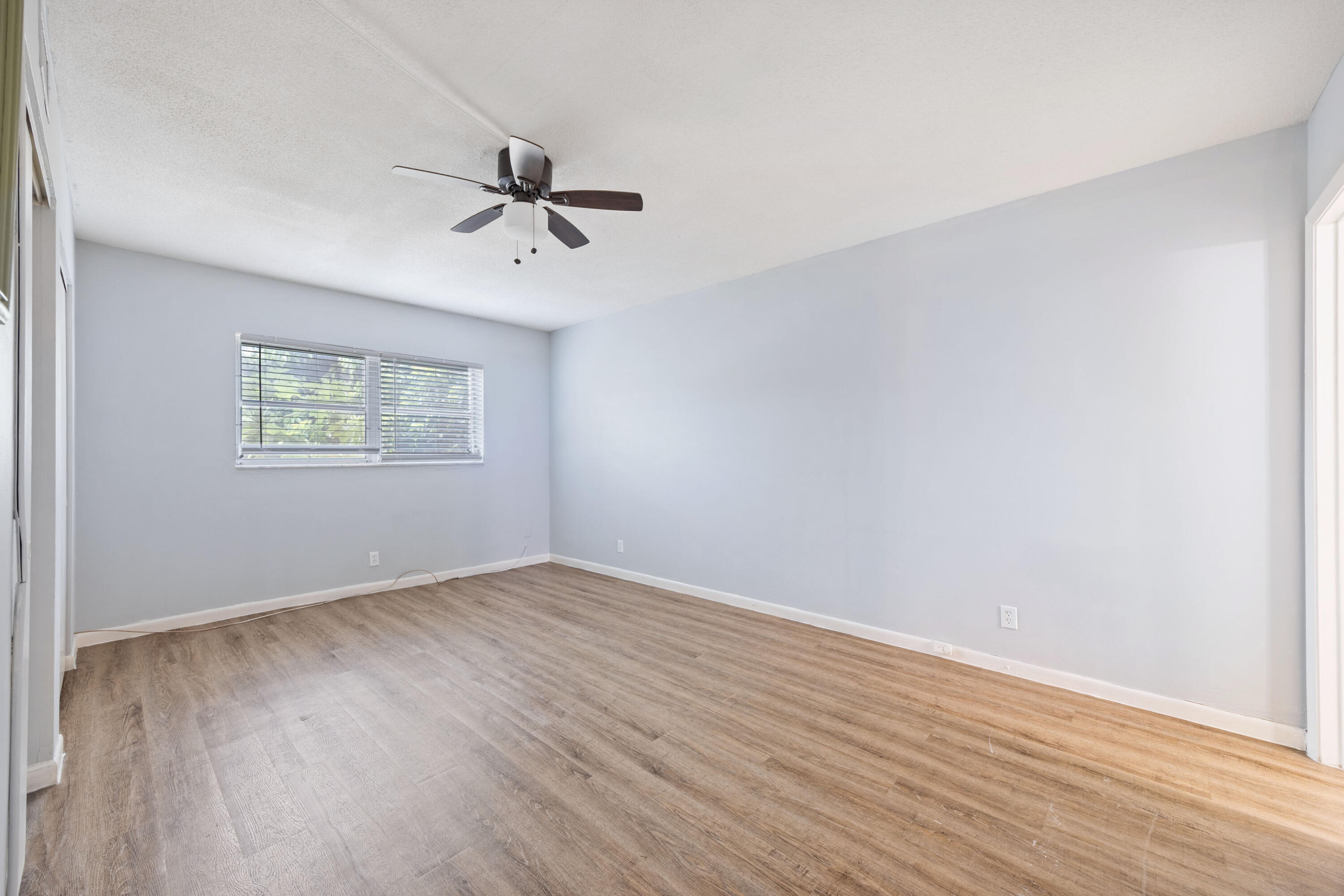 230 Northeast 26th Avenue, Unit 206 Boynton Beach, FL 33435 - Photo 10 of 25 an empty room with wooden floor ceiling fan and windows