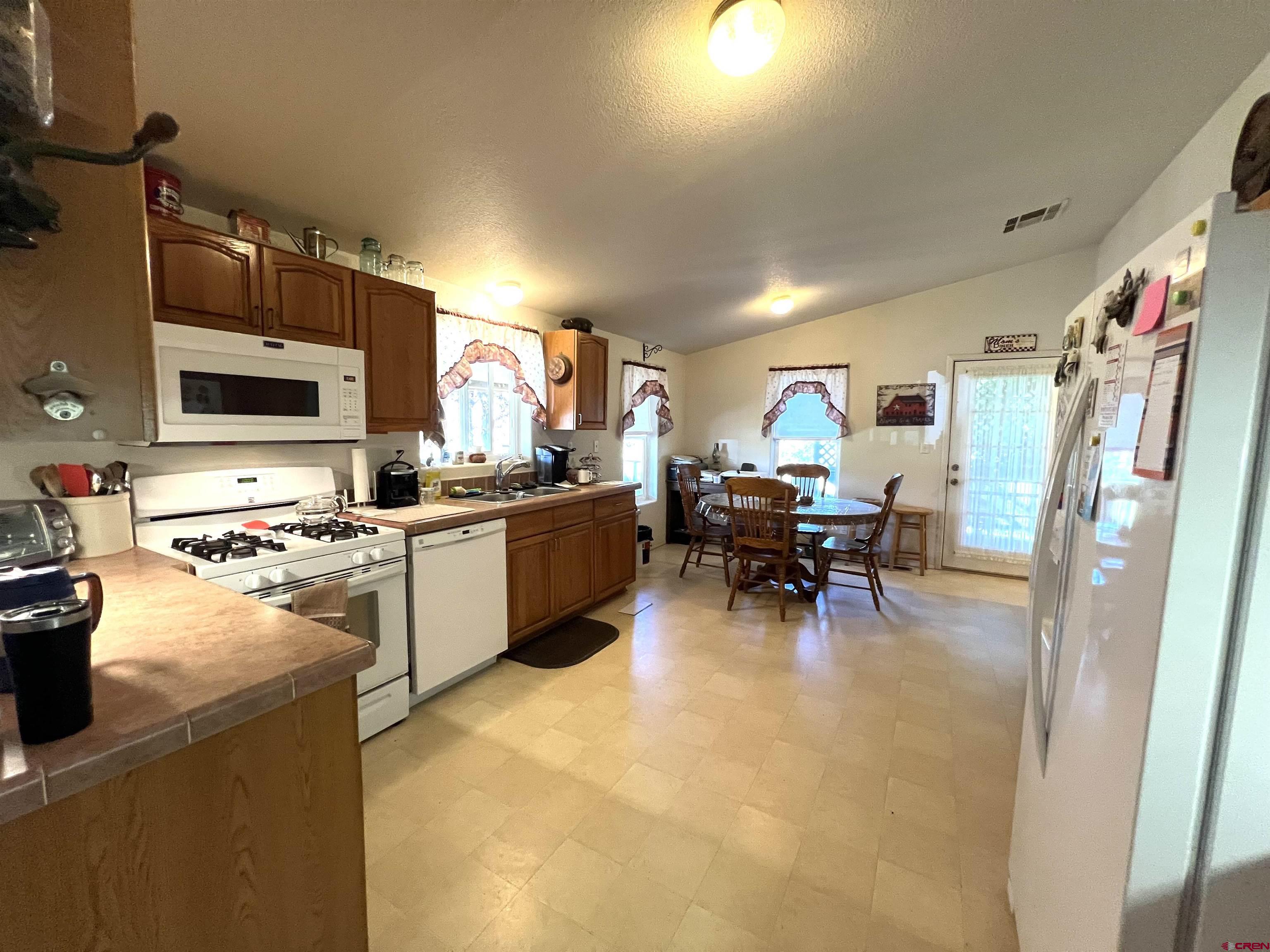 21179 Rd C.6 Cortez, CO 81321 - Photo 6 of 33 a kitchen with a sink a stove and chairs with wooden floor