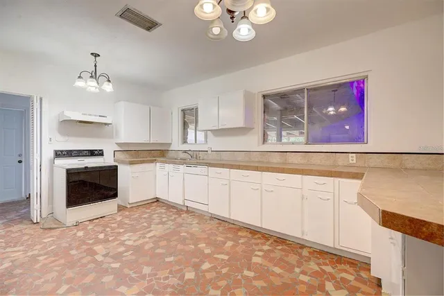 a kitchen with granite countertop a stove top oven sink and cabinets