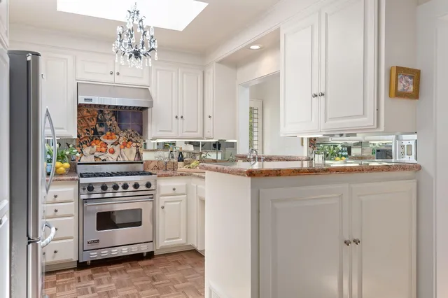 a kitchen with stainless steel appliances a stove a sink cabinets and a window