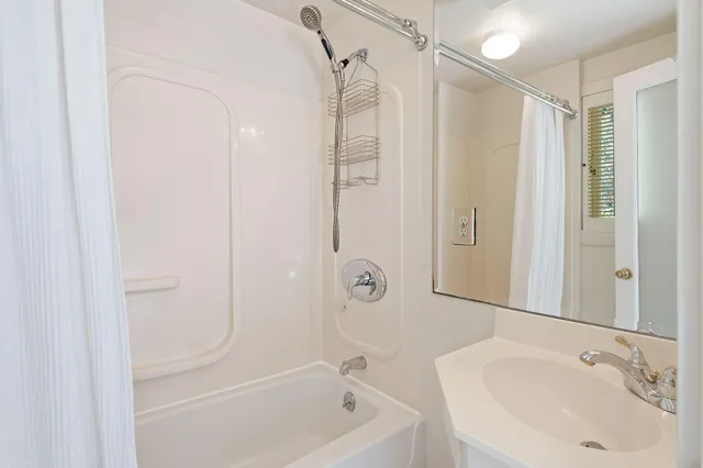 a bathroom with a tub shower vanity and a sink