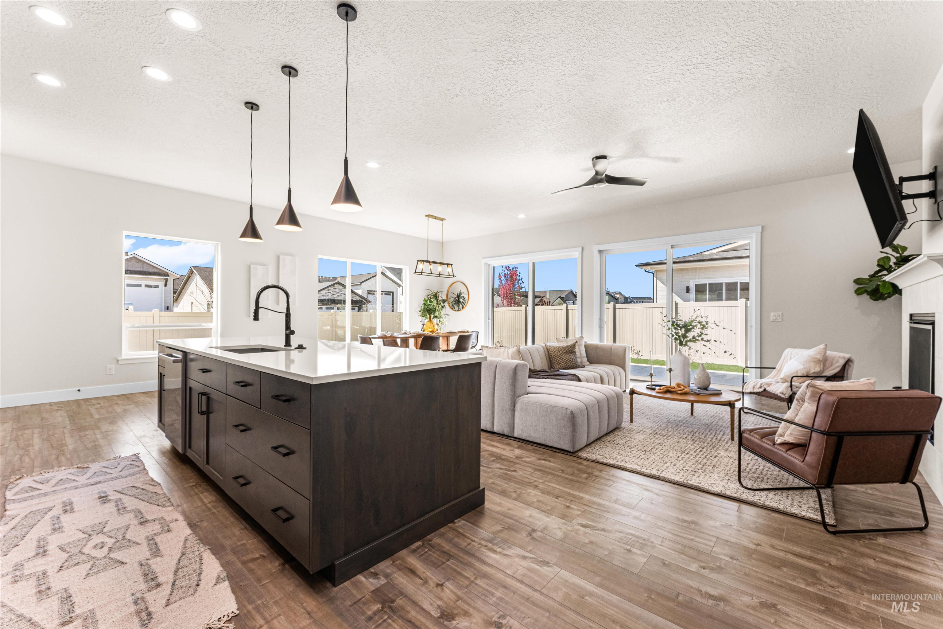 2787 West Warlander Street Meridian, ID 83642 - Photo 33 of 34 Kitchen with dark wood finish cabinets, light wood-type flooring, open floor plan, a glass covered fireplace, and an island with sink