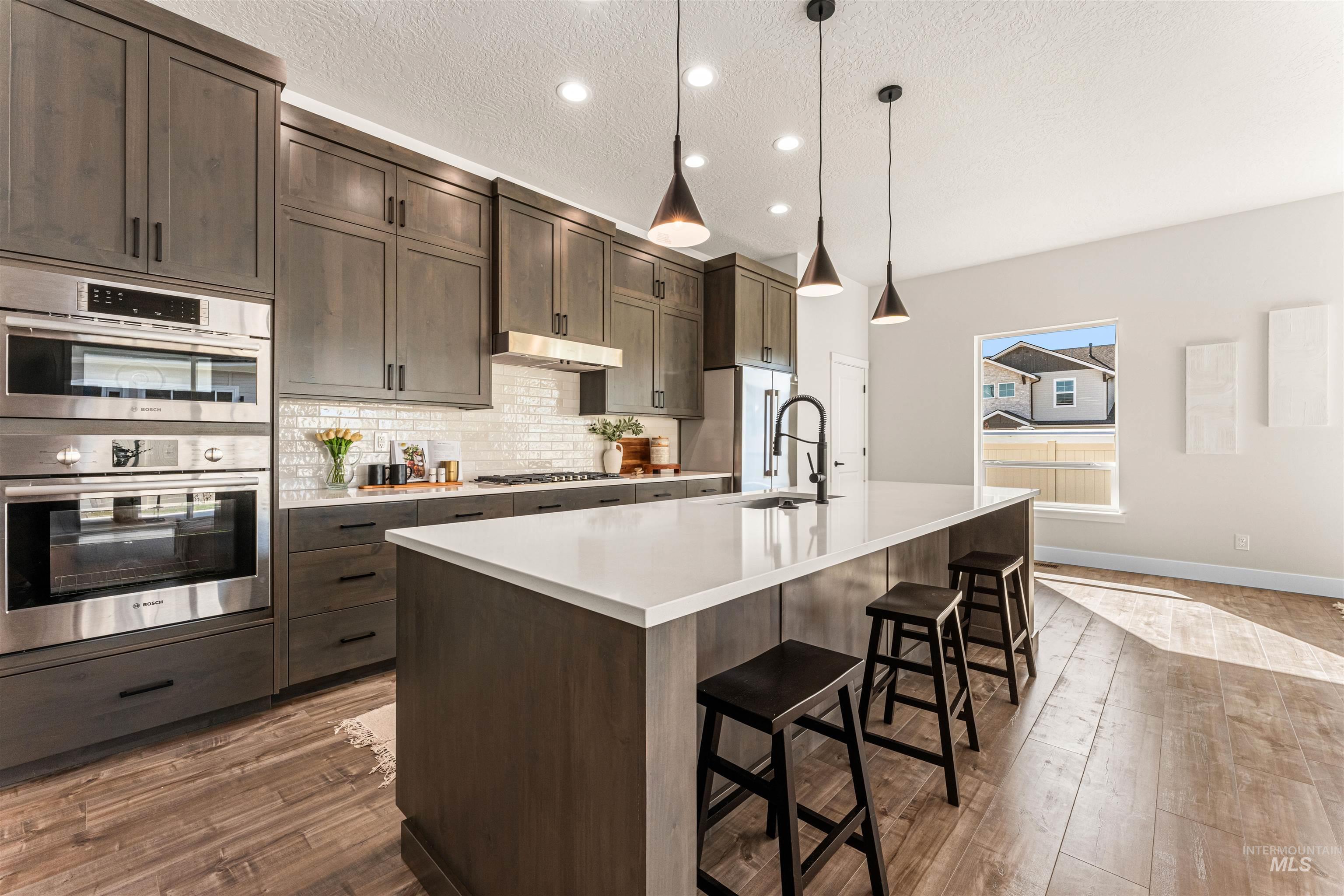 2787 West Warlander Street Meridian, ID 83642 - Photo 10 of 34 Kitchen featuring a breakfast bar area, stainless steel appliances, pendant lighting, a center island with sink, and dark wood-style flooring