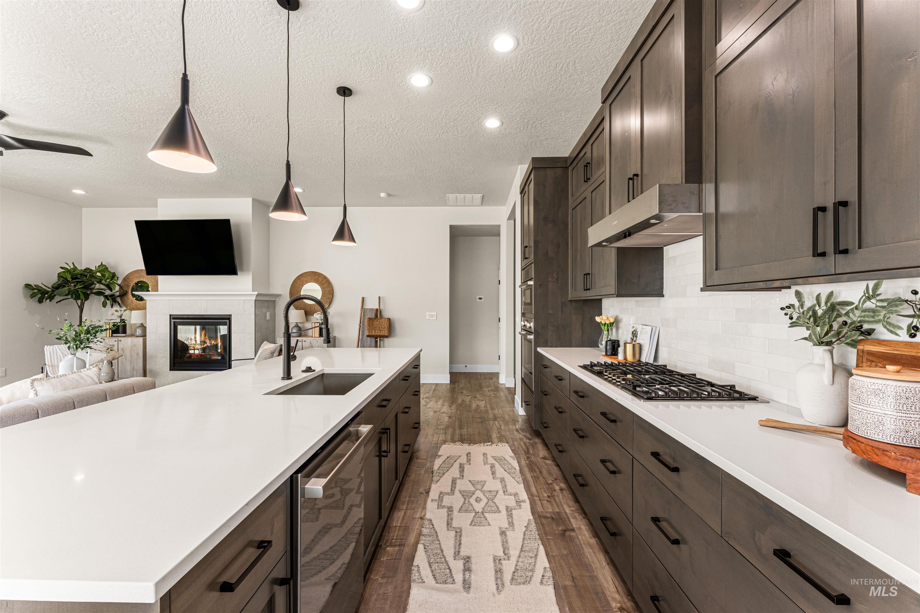 2787 West Warlander Street Meridian, ID 83642 - Photo 34 of 34 Kitchen featuring open floor plan, dark wood finish cabinetry, a tile fireplace, dark wood-style flooring, and stainless steel appliances