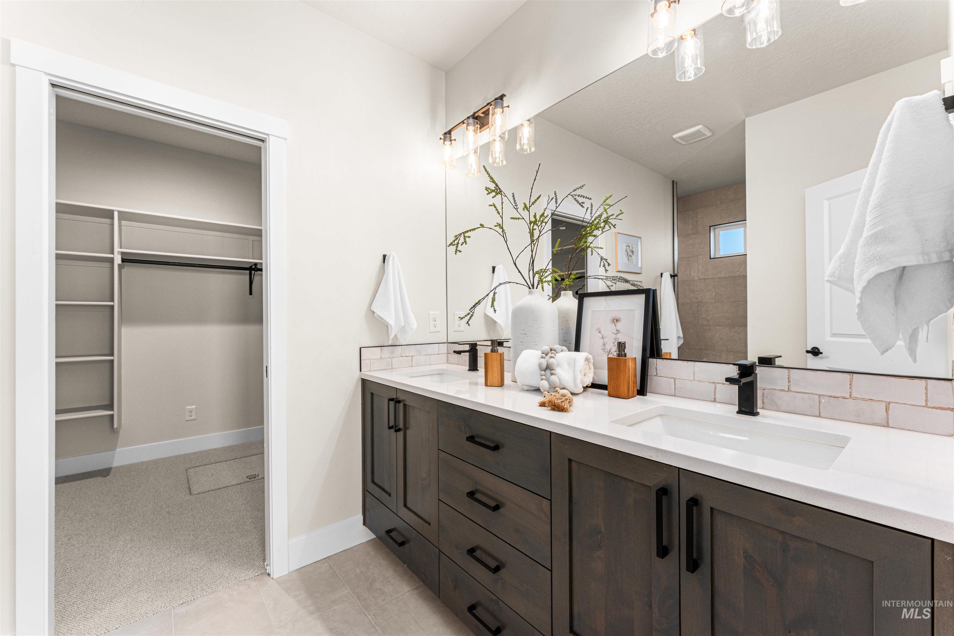 2787 West Warlander Street Meridian, ID 83642 - Photo 16 of 34 Full bath featuring double vanity, a walk in closet, light tile patterned flooring, light colored carpet, and backsplash