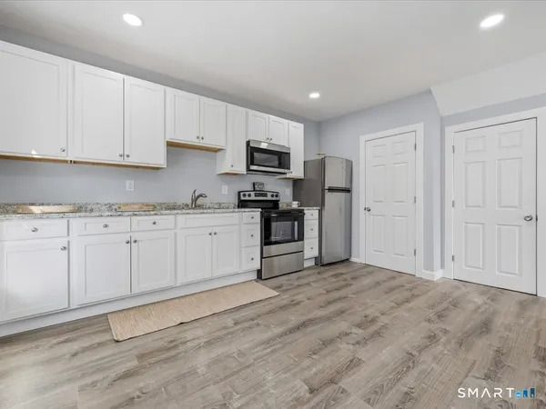 a kitchen with granite countertop white cabinets and stainless steel appliances