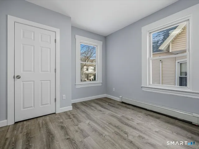 a view of an empty room with a window and wooden floor