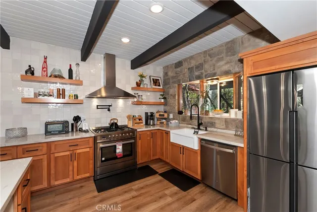 a kitchen with stainless steel appliances granite countertop a refrigerator a sink dishwasher a stove and white countertops with wooden floor