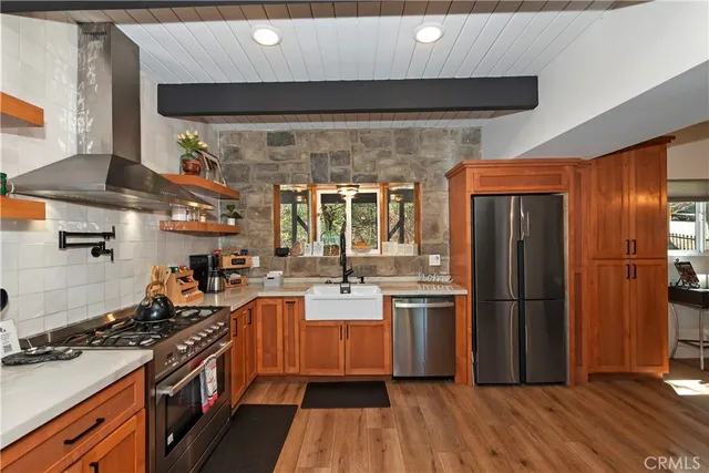 a kitchen with stainless steel appliances a stove a refrigerator and wooden floor