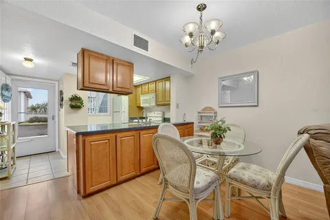 a dining room with wooden floor a chandelier a glass table and chairs