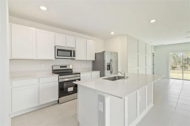 a kitchen that has a lot of white cabinets and stainless steel appliances