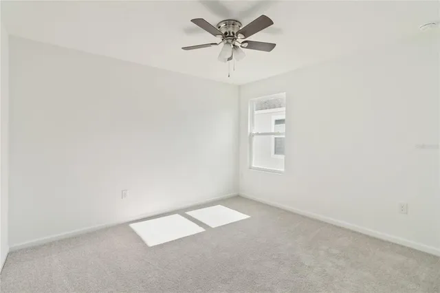 an empty room with a window and a ceiling fan