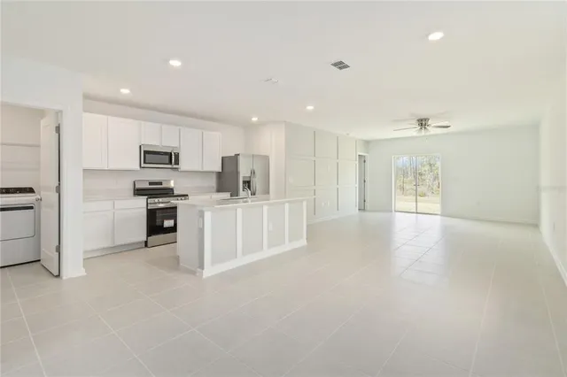 a view of a kitchen with a sink and dishwasher a refrigerator with white cabinets