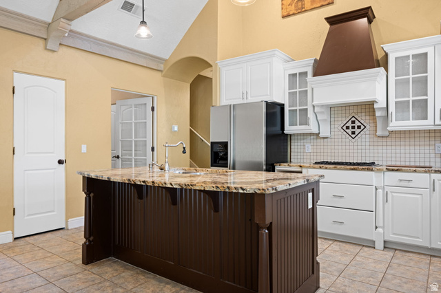 20 Valley Road Leeds, UT 84746 - Photo 5 of 57 Kitchen featuring a central island with a stone countertop and integrated sink, white cabinetry, stainless steel refrigerator, and a gas range with a decorative range hood