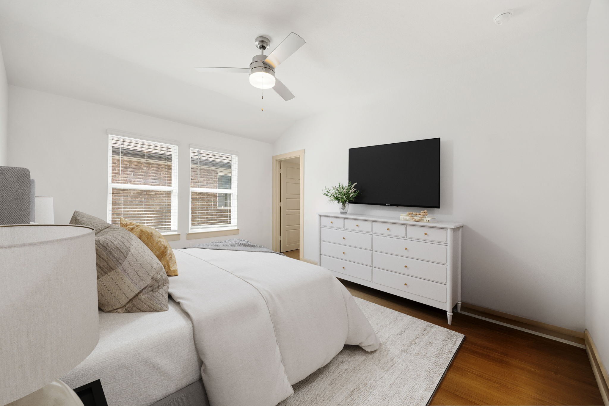 711 Alpine Fls Road Rosharon, TX 77583 - Photo 9 of 20 Retreat to the expansive primary suite, a bright and peaceful sanctuary designed for ultimate relaxation. Large windows bathe the room in soothing natural light. This spacious retreat features neutral walls and warm flooring, creating a clean, sophisticated canvas that easily accommodates large furniture. It’s the perfect private escape at the end of a long day.
