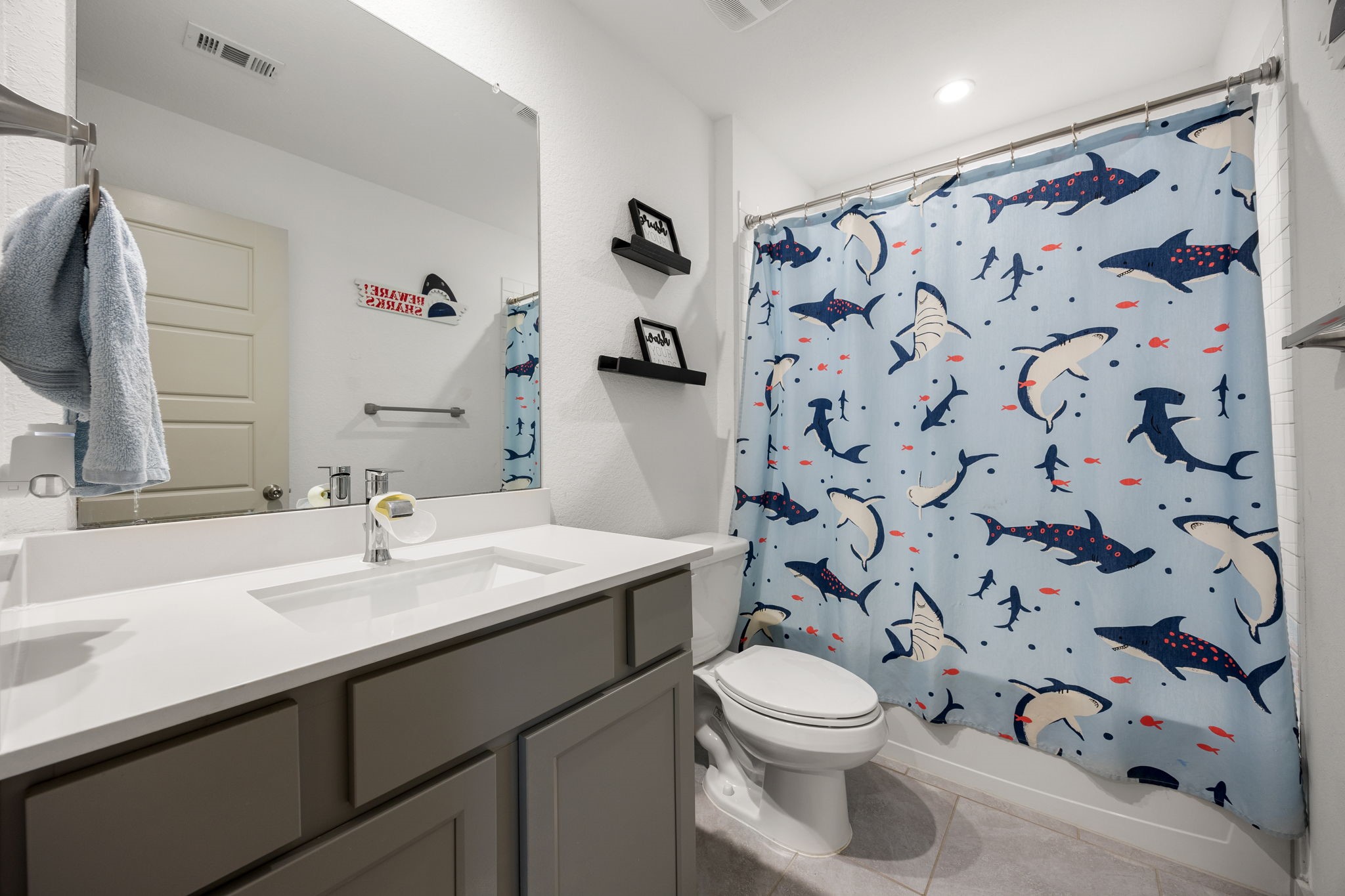 711 Alpine Fls Road Rosharon, TX 77583 - Photo 14 of 20 The secondary bathroom is thoughtfully designed with modern finishes, featuring a sleek vanity with stylish grey cabinetry and a crisp white countertop. The space is anchored by durable, large-format floor tile and includes a versatile tub-and-shower combination. Bright and clean, this well-appointed bathroom offers both functionality and a contemporary aesthetic for family and guests alike.