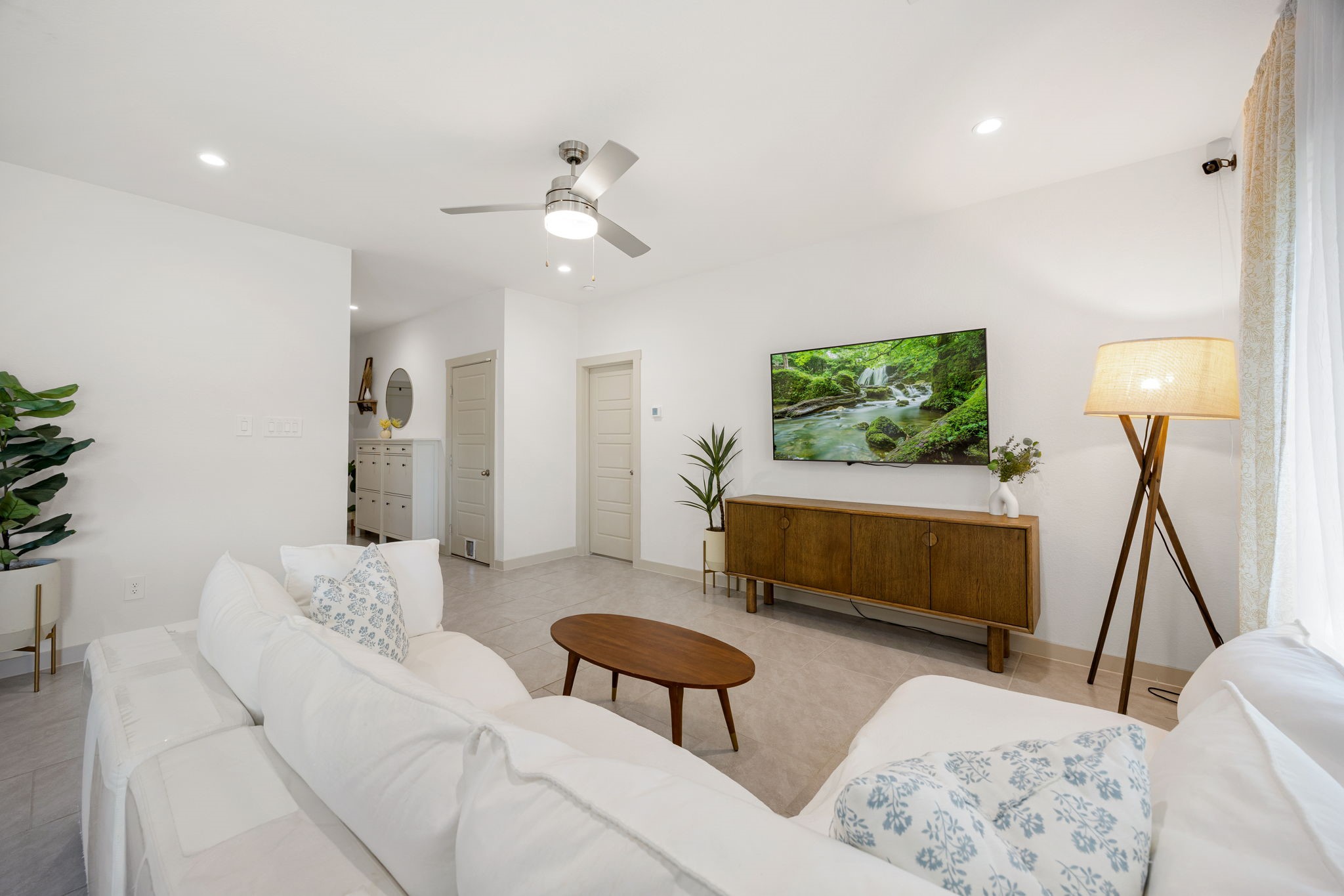 711 Alpine Fls Road Rosharon, TX 77583 - Photo 4 of 20 This expansive, open-concept living area is the heart of the home, offering a bright and airy atmosphere perfect for modern life. Large-format neutral tile flooring and crisp white walls provide a clean, contemporary canvas that reflects the abundance of natural light streaming through the windows.