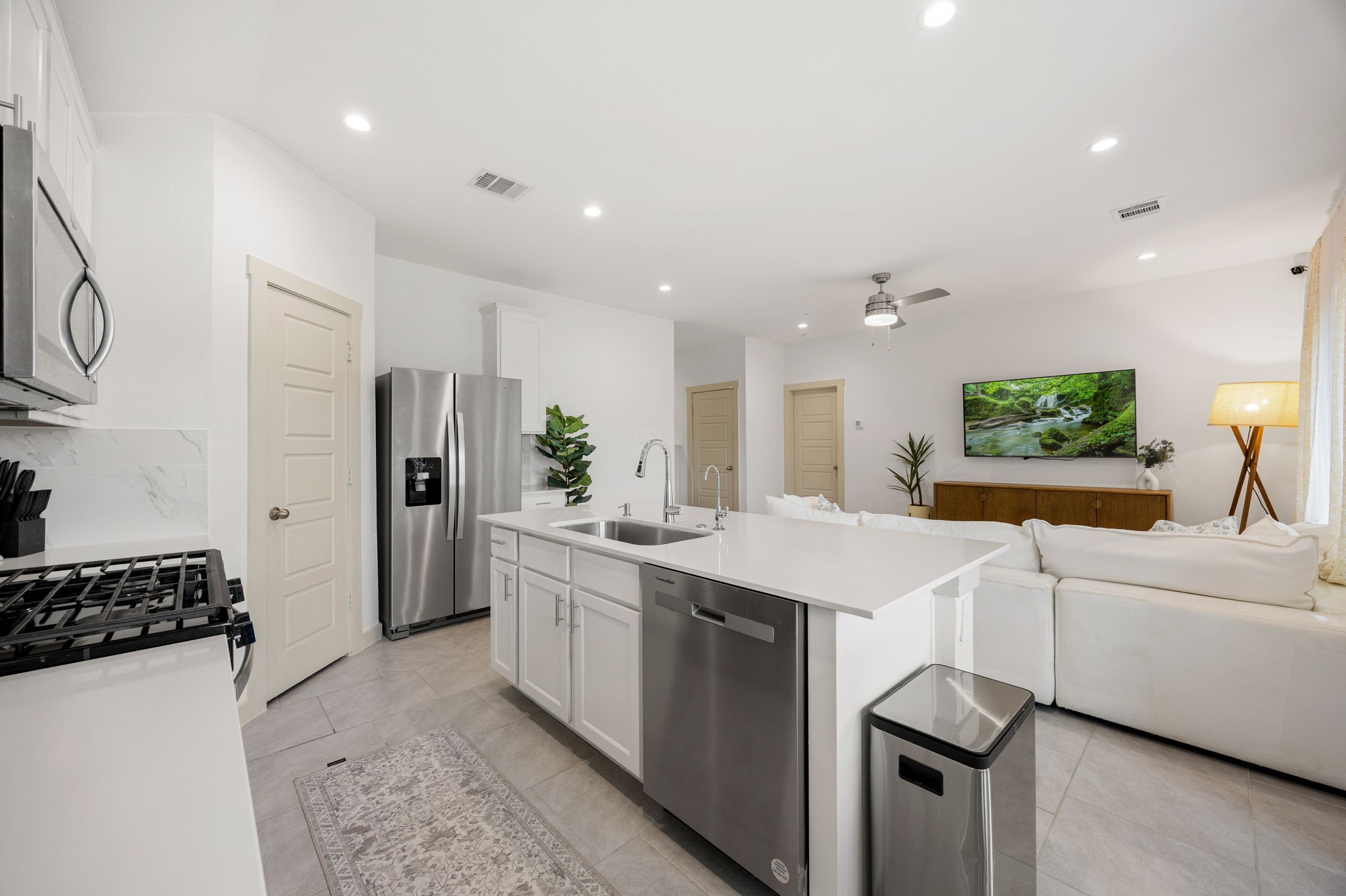 711 Alpine Fls Road Rosharon, TX 77583 - Photo 6 of 20 This gourmet kitchen serves as the sophisticated centerpiece of the home’s open-concept design. It features sleek white cabinetry and luminous quartz countertops that perfectly complement the stainless steel appliance suite, including a built-in microwave and gas range.
