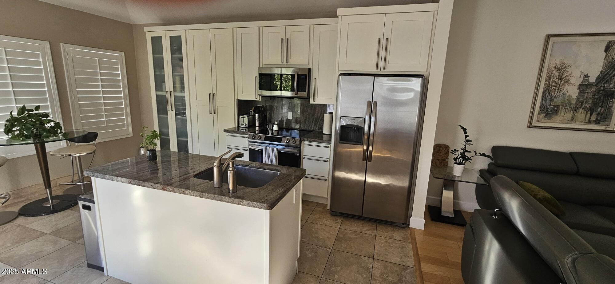7272 East Gainey Ranch Road, Unit 120 Scottsdale, AZ 85258 - Photo 3 of 26 a kitchen with stainless steel appliances granite countertop a refrigerator and a sink