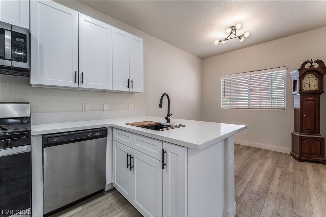 4730 East Craig Road, Unit 1058 Las Vegas, NV 89115 - Photo 12 of 30 A contemporary kitchen features sleek white cabinetry, stainless steel appliances, and a central island with an integrated sink.