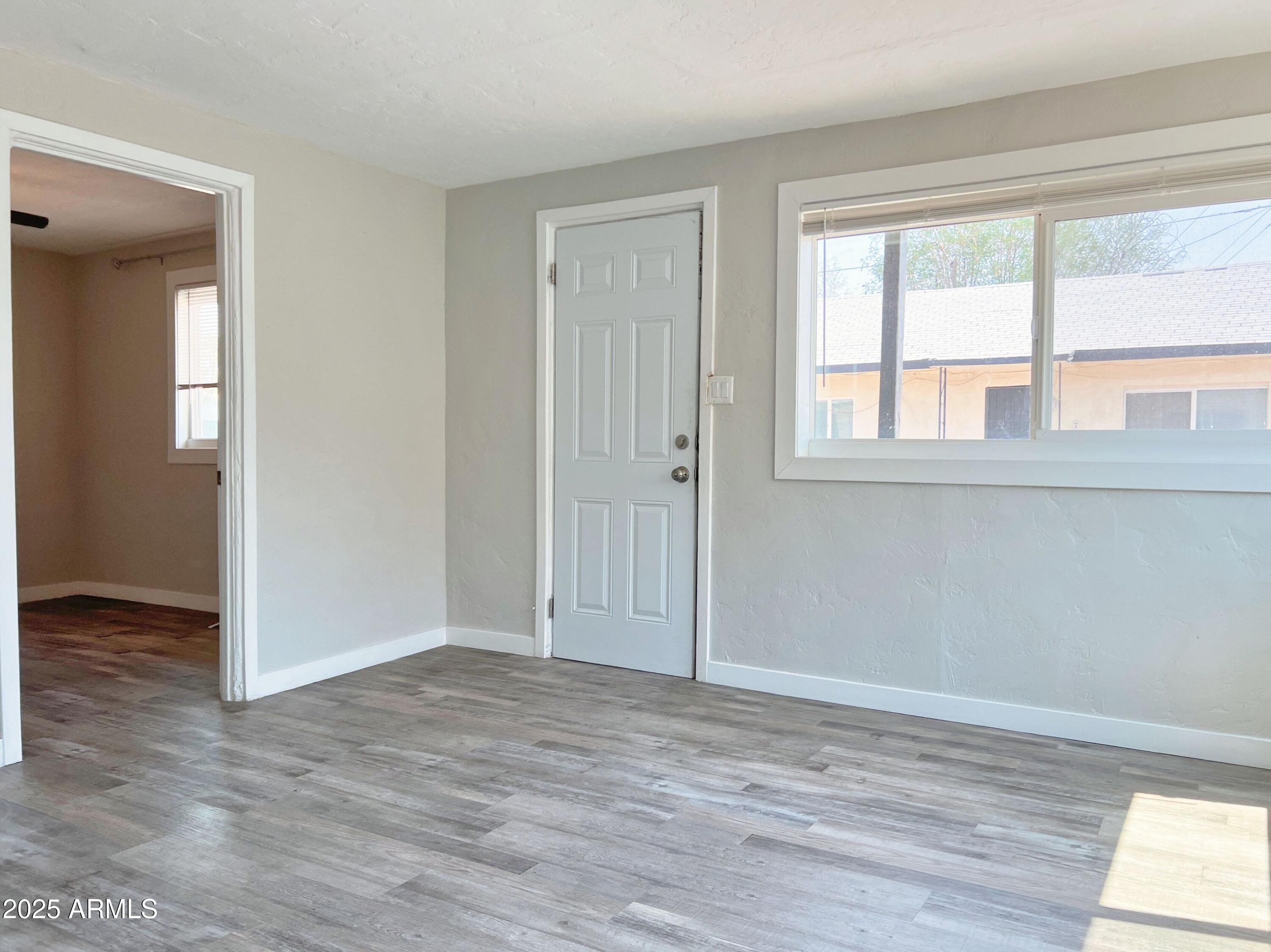 1125 East Devonshire Avenue, Unit 2 Phoenix, AZ 85014 - Photo 4 of 8 an empty room with wooden floor and windows