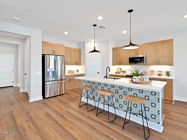 a kitchen with stainless steel appliances granite countertop a sink a stove a refrigerator and island with wooden floor