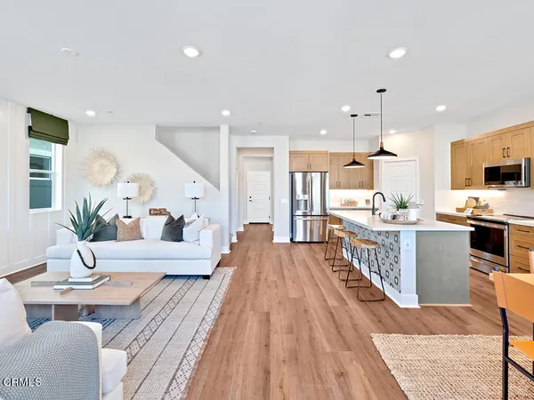 a large white kitchen with wooden floor and stainless steel appliances