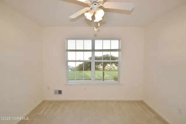 an empty room with a chandelier fan and windows