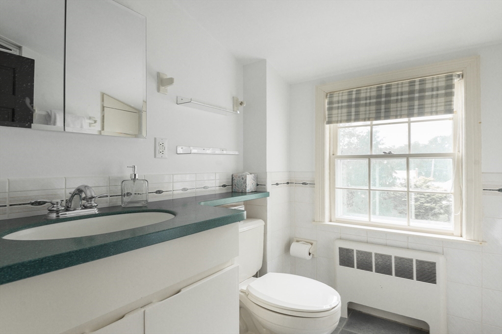 7 Robinson Road Woburn, MA 01801 - Photo 16 of 21 a bathroom with a granite countertop sink toilet a mirror and a window