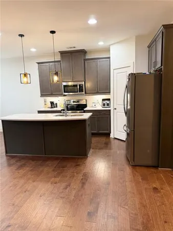a kitchen with stainless steel appliances granite countertop a refrigerator a sink dishwasher a stove with wooden floor