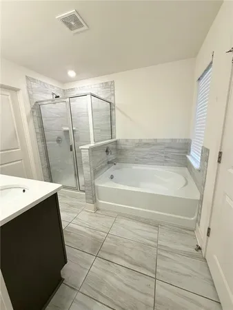 a spacious bathroom with a tub a sink and a mirror