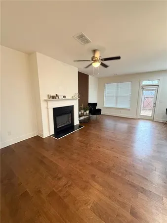 a view of a livingroom with a fireplace a ceiling fan and wooden floor