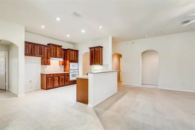 a view of an empty room and kitchen view