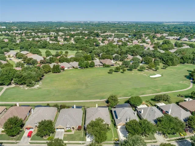 an aerial view of residential houses with outdoor space and trees