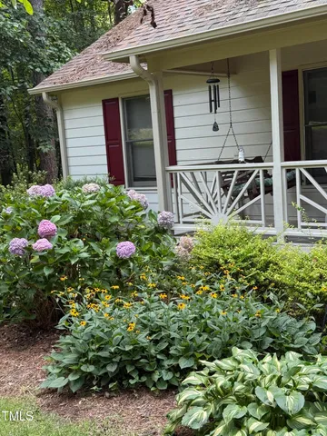 a backyard of a house with fountain plants and large tree