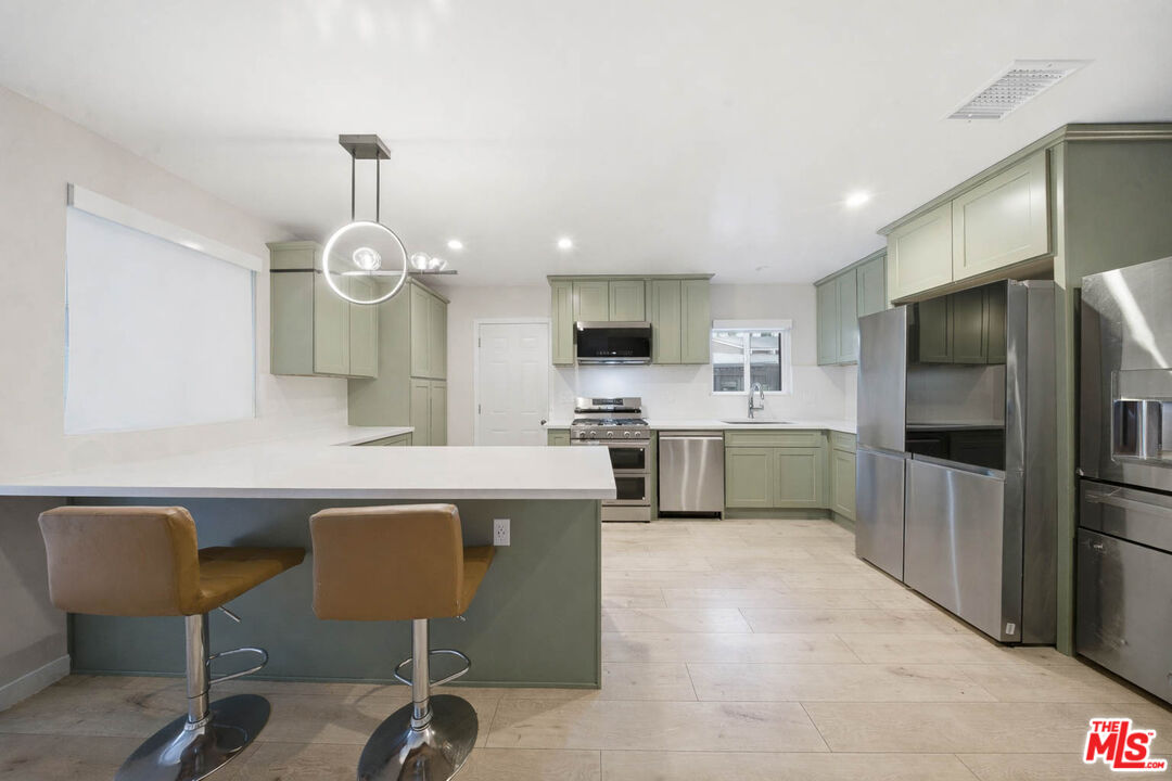 20237 Hartland Street Winnetka, CA 91306 - Photo 5 of 13 a kitchen with cabinets a sink and appliances