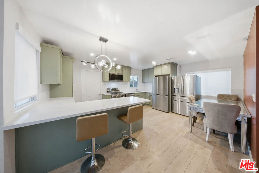 20237 Hartland Street Winnetka, CA 91306 - Photo 6 of 13 a kitchen with kitchen island stainless steel appliances a dining table chairs sink and cabinets