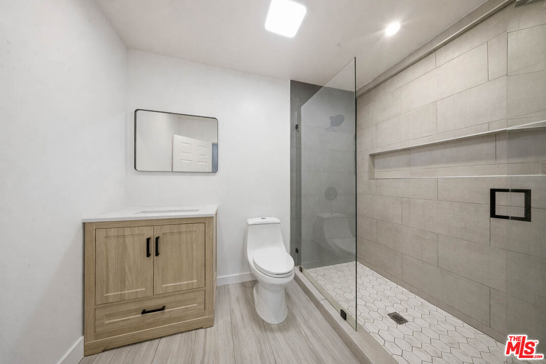 20237 Hartland Street Winnetka, CA 91306 - Photo 8 of 13 a bathroom with a granite countertop toilet a sink and shower