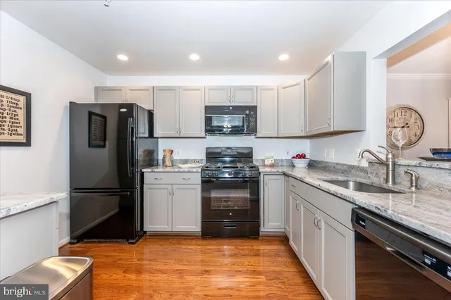 a kitchen with granite countertop a refrigerator stove and sink