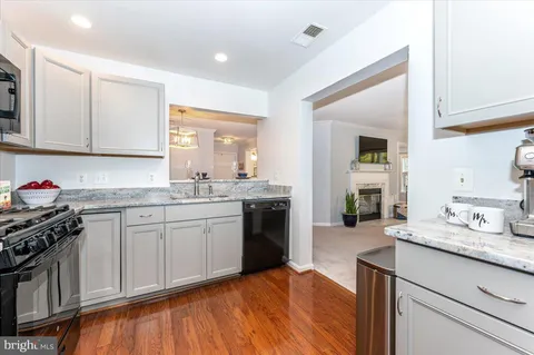 a kitchen with granite countertop a sink cabinets stainless steel appliances and a counter top space