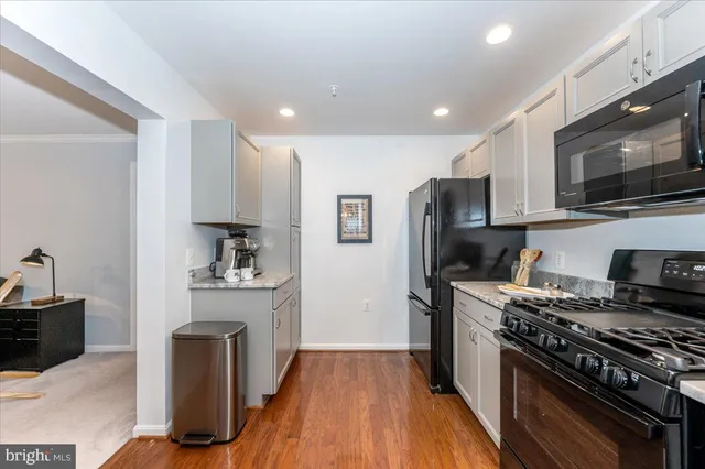 a kitchen with granite countertop a stove top oven a sink dishwasher and a refrigerator with wooden floor