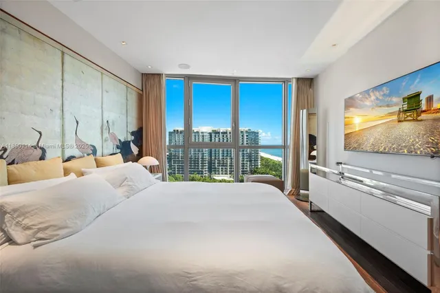 a large bedroom with a large bed and a flat tv screen on dresser