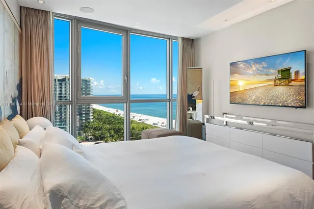 a bedroom with a large bed and a flat tv screen next to a window